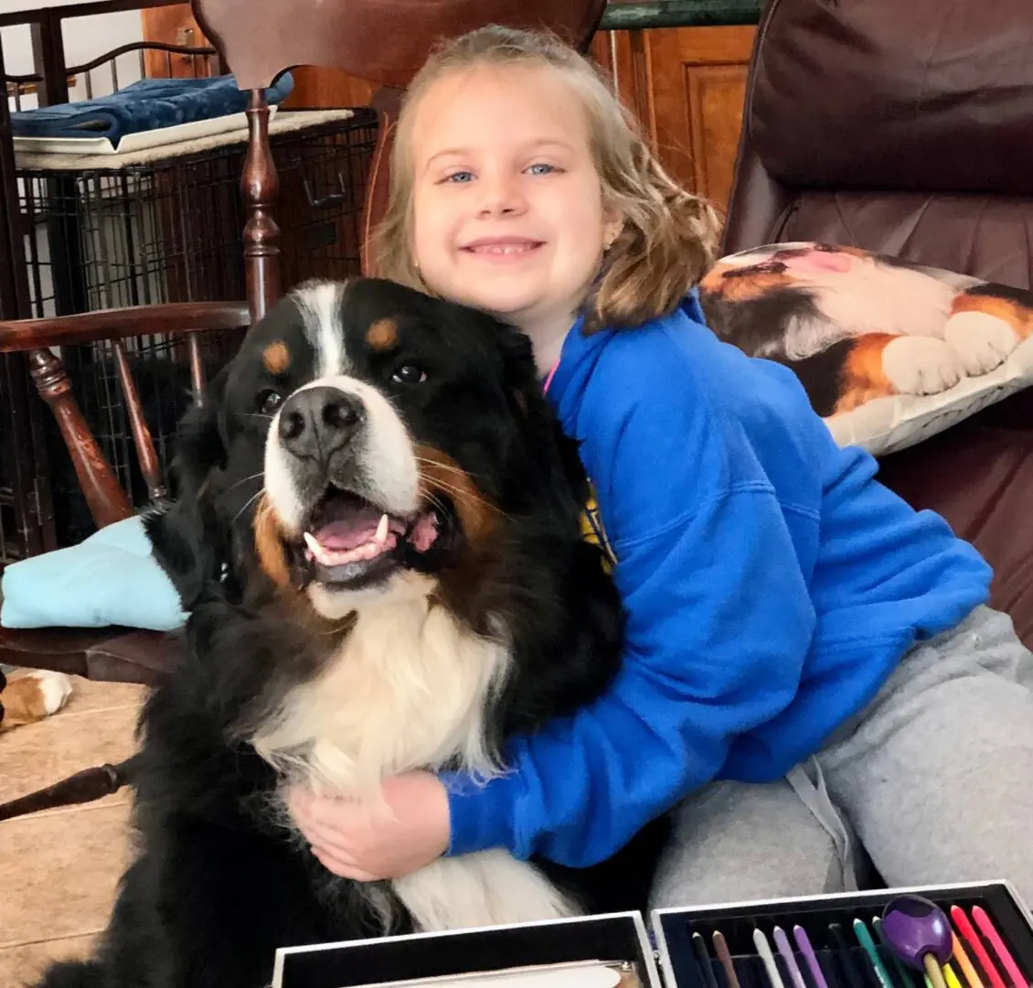 A Kid is Playing With Her Pet Dog While Sitting on the Couch